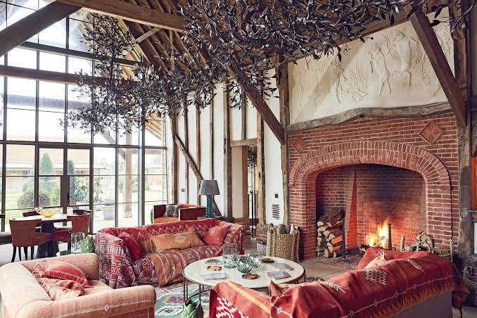 Timber-framed barn lounge with a lit brick fireplace and layered textiles