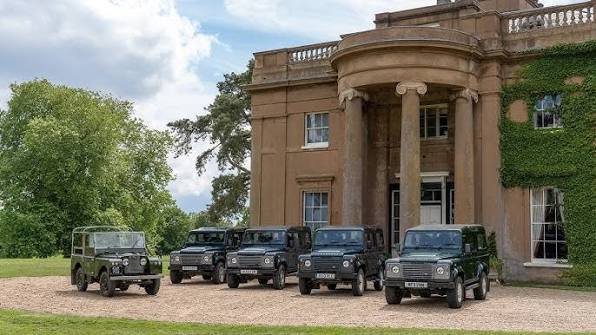 Land Rover Defenders lined up outside the estate's ivy-clad manor house
